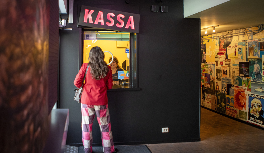 Une femme en veste rouge à la caisse.