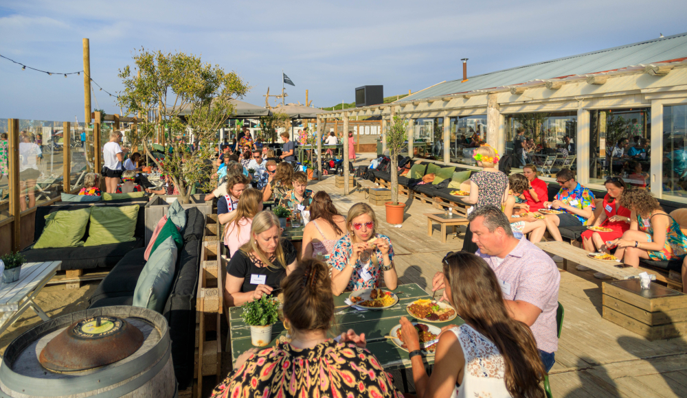 Mensen etend op een terras op het Noorderstrand van Scheveningen
