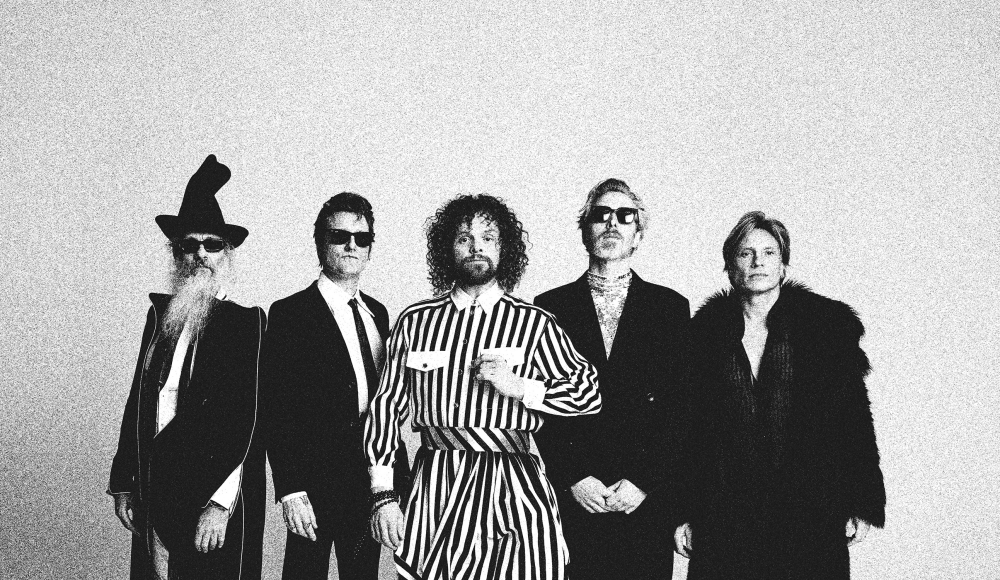 Fünf Personen in auffälliger Kleidung, darunter ein gestreifter Overall.