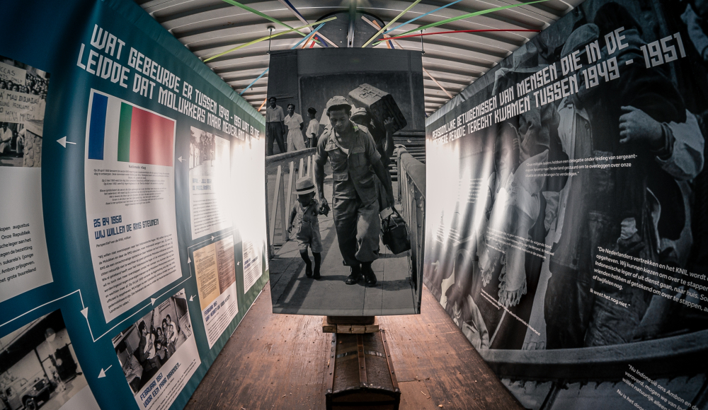A photo of a man carrying luggage in an exhibition 75 Years of Moluccans in the Netherlands Foto: Ed Leatemia