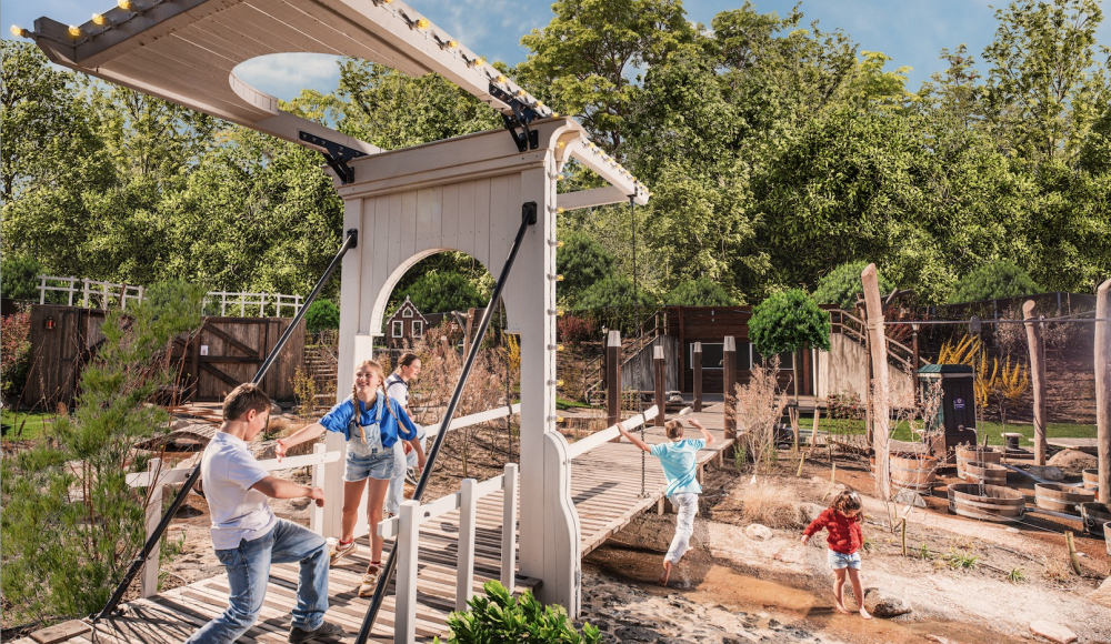 Des enfants jouent dans un parc de jeux extérieur verdoyant avec une structure de jeu.