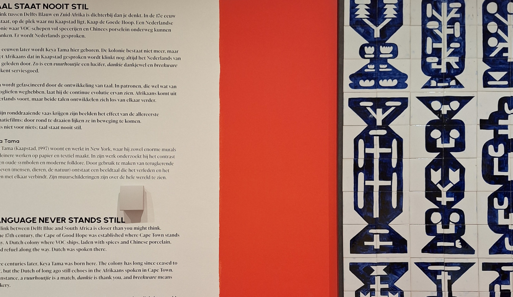 Een kunstwerk met abstracte blauwe patronen op een rode muur.