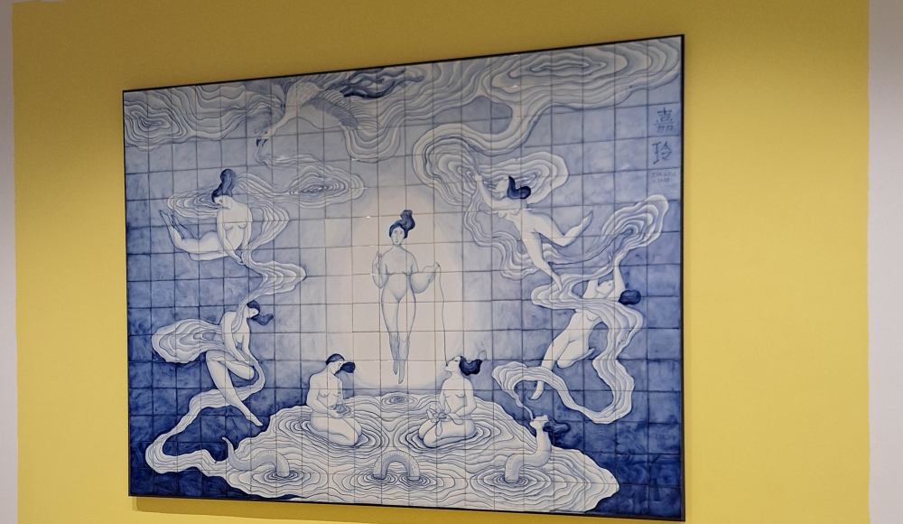 Muurschildering met vrouwen in blauwe tinten op een gele muur