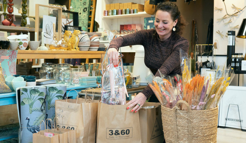 Verkoopster van 3&60 die met een lach op haar gezicht cadeautjes inpakkt. 