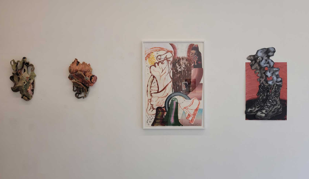 Drie kunstwerken aan een witte muur, waaronder een ingelijste afbeelding.