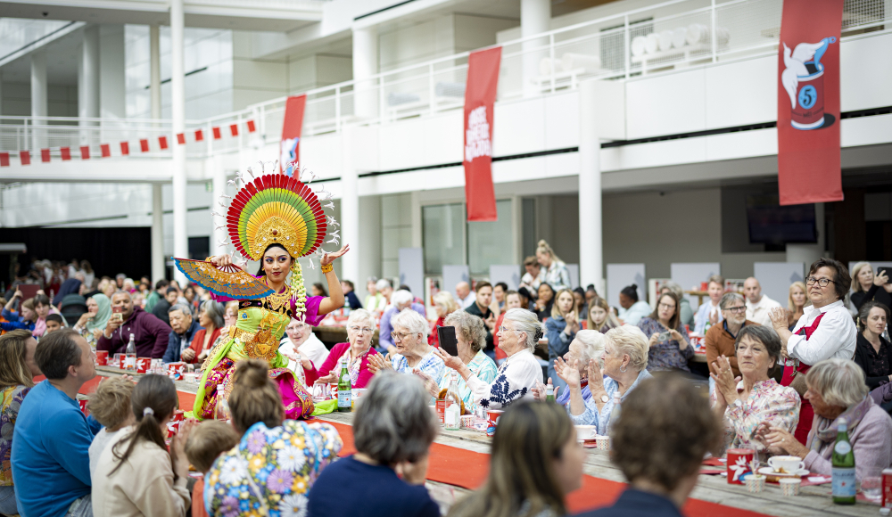 Dansperformer in kleurrijke outfit voor een publiek tijdens een evenement.