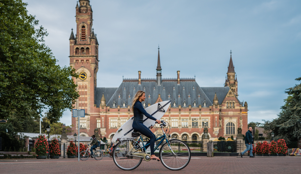 Surfer op de fiets voor het Vredespaleis 