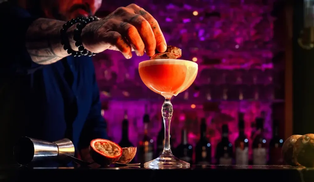 Een barman maakt een cocktail met passievrucht.