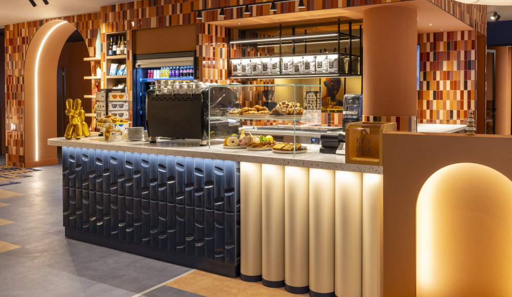 Binnenkant van een koffiebar met snacks en een gekleurde wand.