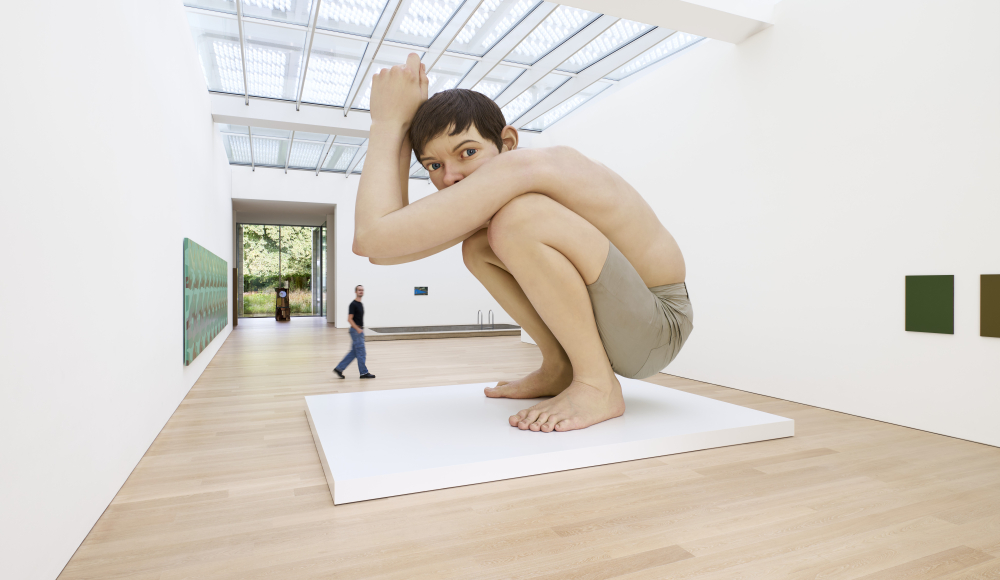 Een jongen in een foetushouding op een witte sokkel in een museum. Voorlinden, gallery view Celebrating the Icons of Art Passage © Antoine van Kaam