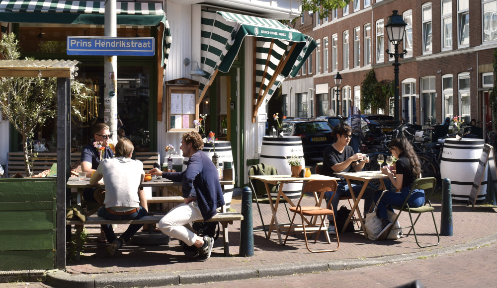 Mensen zitten te eten en te drinken op het terras By Rem in de Prins Hendrikstraat in Den Haag