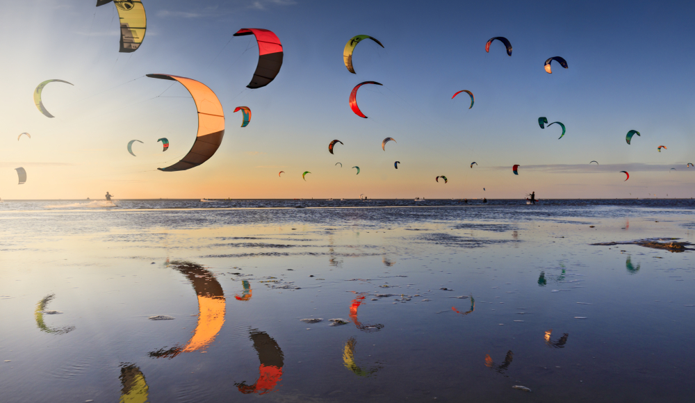Een lucht vol kites van kitesurfers op het strand van de Zandmotor bij Kijkduin