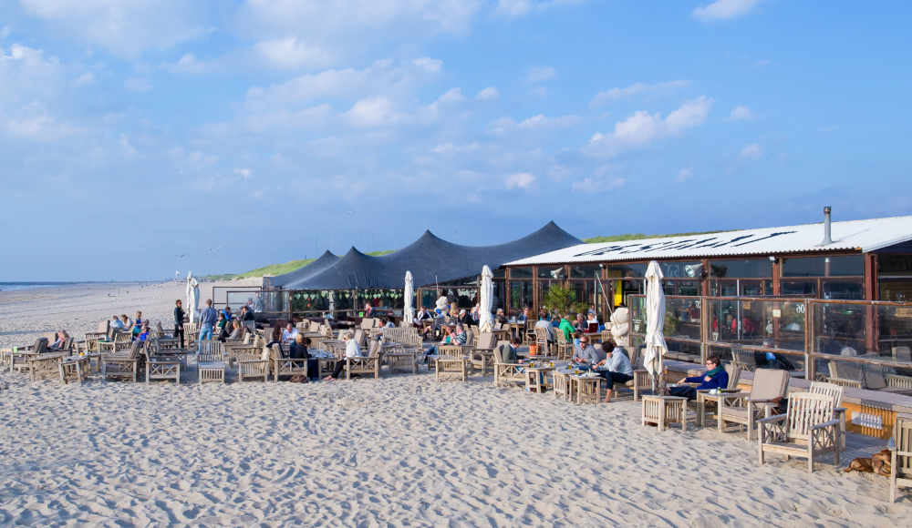 Terras met mensen bij strandpaviljoen de Staat op het Zuiderstrand