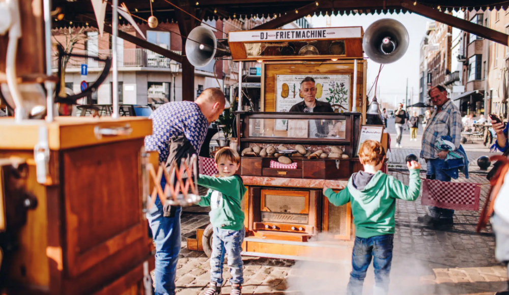 Een frietkraam met een man die friet serveert aan twee kinderen.