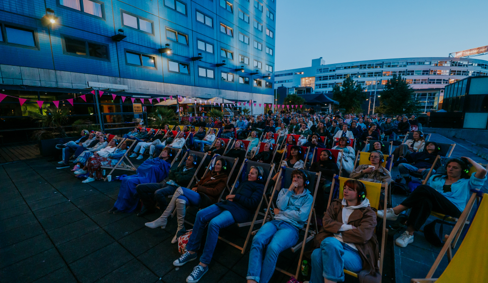 Een groep mensen zit in ligstoelen tijdens een buitenfilm.
