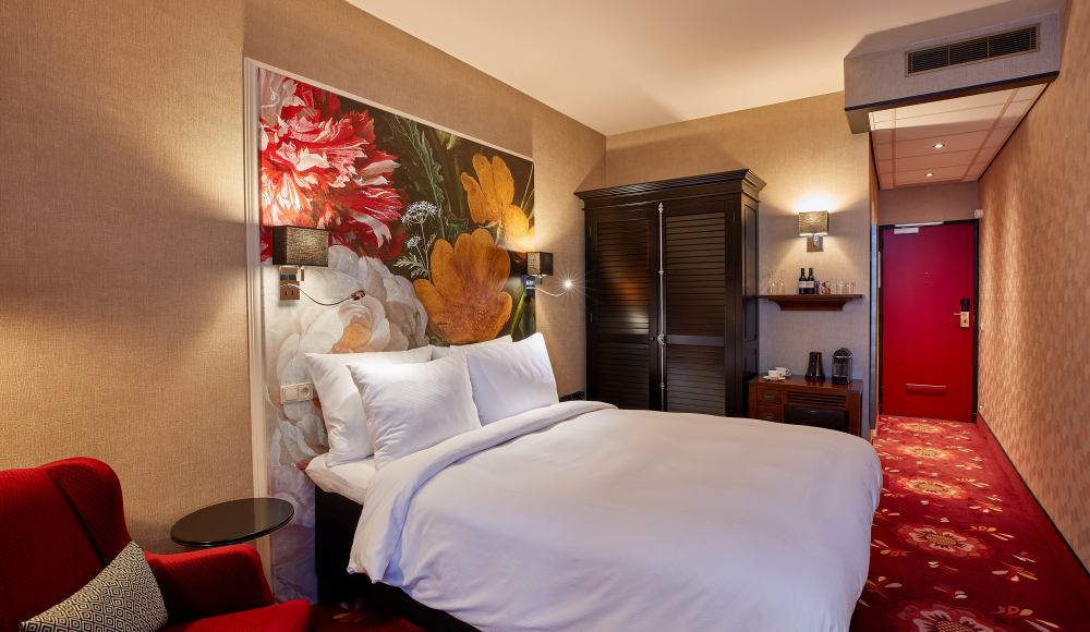 Hotelkamer met warm design, bloemenmuur, rood tapijt en luxe tweepersoonsbed Hotelkamer met warm design, bloemenmuur, rood tapijt en luxe tweepersoonsbed