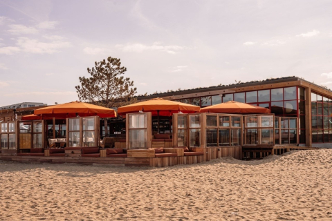 Strandpaviljoen met oranje parasols aan zee (c) Lotte van Uitert