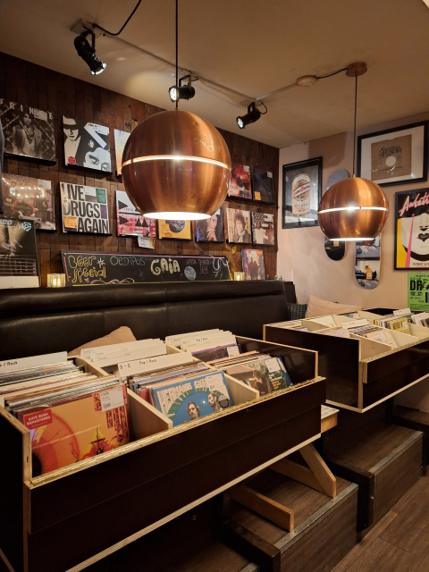 Ontspannen platenzaak met sfeerverlichting. Een gezellige ruimte met platenrekken en gouden lampen.