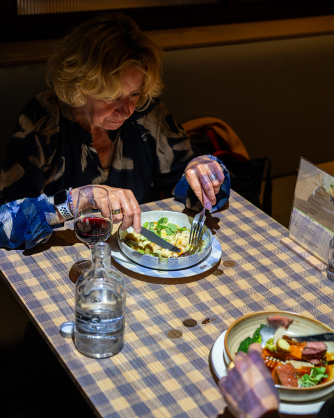 Een vrouw eet met een vork in een restaurant.