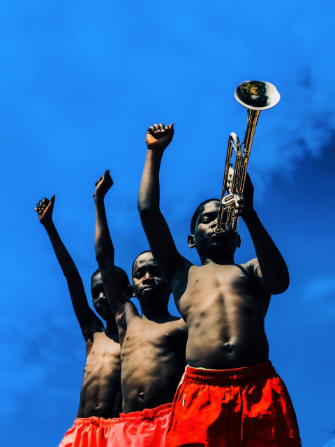 Drie kinderen met opgestoken armen en een trompet onder een blauwe lucht. Derrick Ofosu Boateng, Music Makes The Pain Fade, 2019