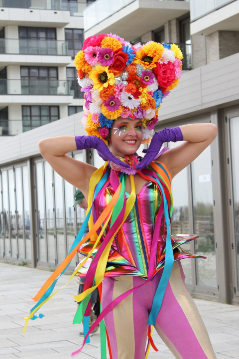 Een dansende performer met een bloemenhoed en kleurrijke kleding.