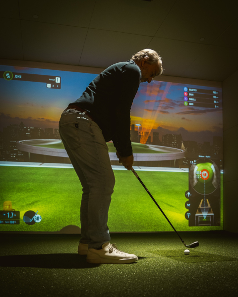 A man is poised to hit a golf ball in a simulator.