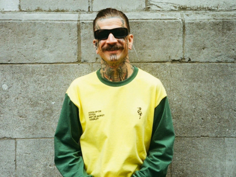 Man met tattoos in de nieuwe collectie van Groen Gele Aderen poseert met een glimlach. Man met tattoos in de nieuwe collectie van Groen Gele Aderen poseert met een glimlach.
