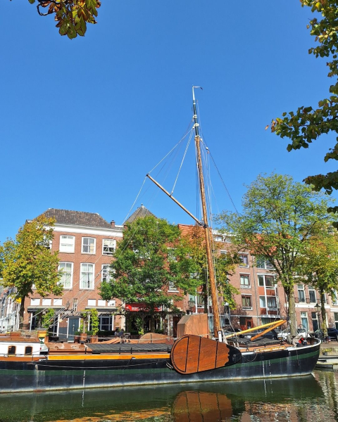 Houten boot op een rustige gracht met huizen op de achtergrond