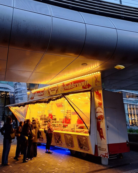 Mensen staan in de rij bij een gebakkraam in de avond.