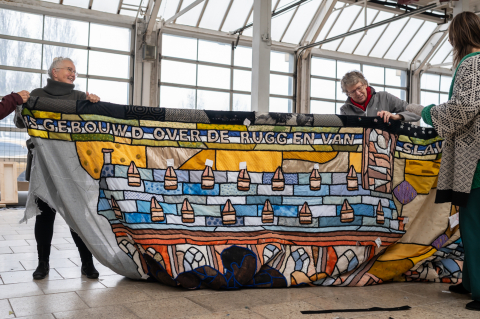 Vijf mensen tonen een groot textielkunstwerk.