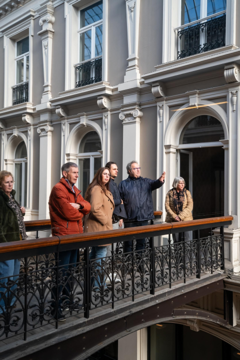 Vijf mensen kijken naar beneden vanaf een balkon.