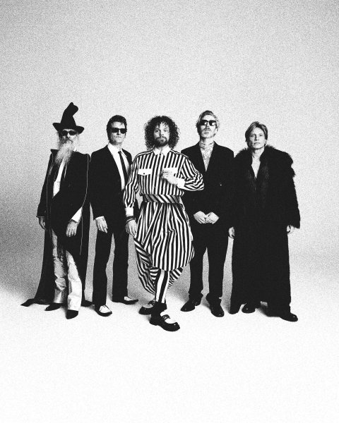 Vijf mensen in opvallende kleding, inclusief een gestreepte overall.