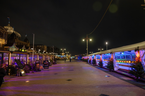 Die Strandpromenade in Scheveningen mit Festbeleuchtung und Menschen.