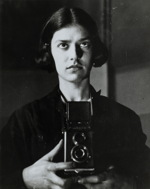 Une jeune femme avec des cheveux mi-longs tient un appareil photo.