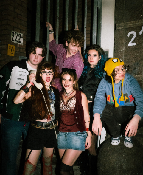 Zes jongeren poseren in retro outfits, met gadgets.