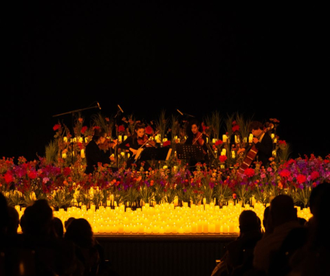 Musici spelen op een podium omgeven door bloemen en kaarsen.