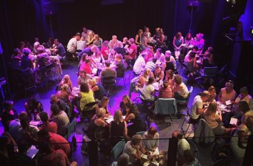 De theaterzaal vol met mensen aan tafels voor de Pubquiz