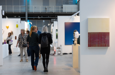 Bezoekers in een hal met kunstwerken tijdens Art The Hague