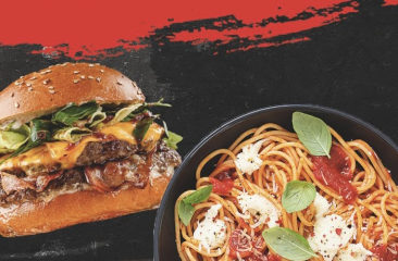 Een goed gevuld broodje cheeseburger en een bordje spaghetti met tomatensaus en baslicumblaadjes
