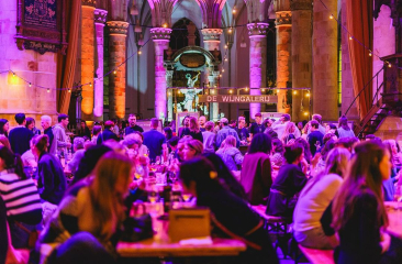 Bezoekers van Het Wijn Festijn in de Grote Kerk aan tafels