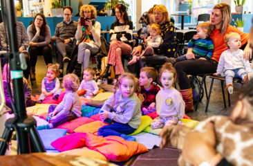 Kinderen en ouders luisteren naar een verhaal uit een boek