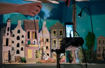 Een miniatuurtheaterset met marionettenpoppen en een decor van kartonnen huizen