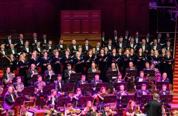 Orkest en koor voeren muziekstuk uit op podium (c) World Concerts 
