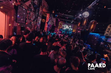 Drukke dansvloer in het Paardcafé in Den Haag, met feestende mensen, kleurrijke verlichting en een levendige sfeer.