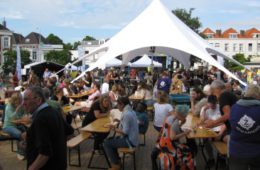 Prins Hendrikplein tijdens Zeeheldenfestival met tent, eettafels en gezellige sfeer.