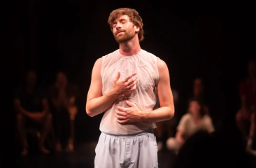Philip Cahrpit staat op het podium in zijn theatervoorstelling Wanderlust. Hij draagt lichte losse kleding en heeft zijn ogen dicht. 