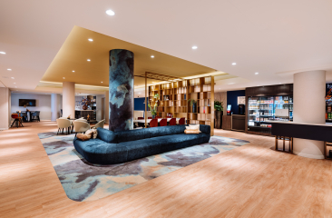 De moderne lobby van het Novotel World Forum met luxe zithoeken, warme verlichting en een stijlvolle bar met drankencollectie. De moderne lobby van het Novotel World Forum met luxe zithoeken, warme verlichting en een stijlvolle bar met drankencollectie.