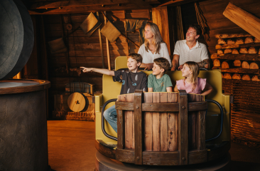 gezin met 2 jongens en een meisje in een attractie wagon in de vorm van een houten ton.