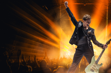 Rockzanger met gitaar voor juichend publiek op podium (c) We Will Rock You 