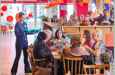 Buurtbewoners lunchen samen aan een lange tafel